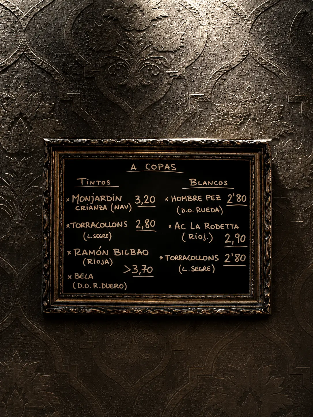 La pissarra de vins a copes del Síbaris, escrita a mà i emmarcada sobre la paret ornamental